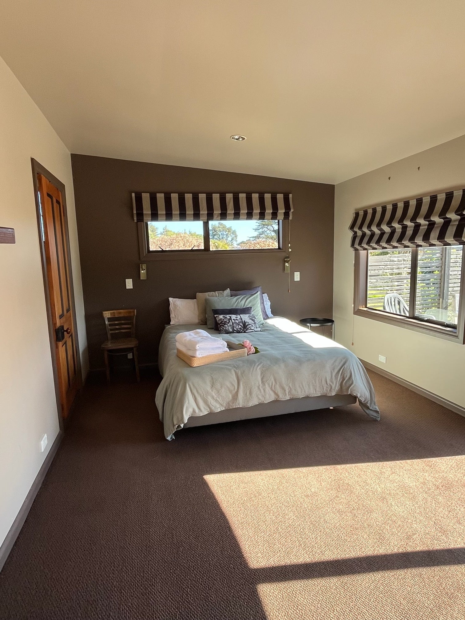 Studio room with a luxury queen bed, windows, and a chair.